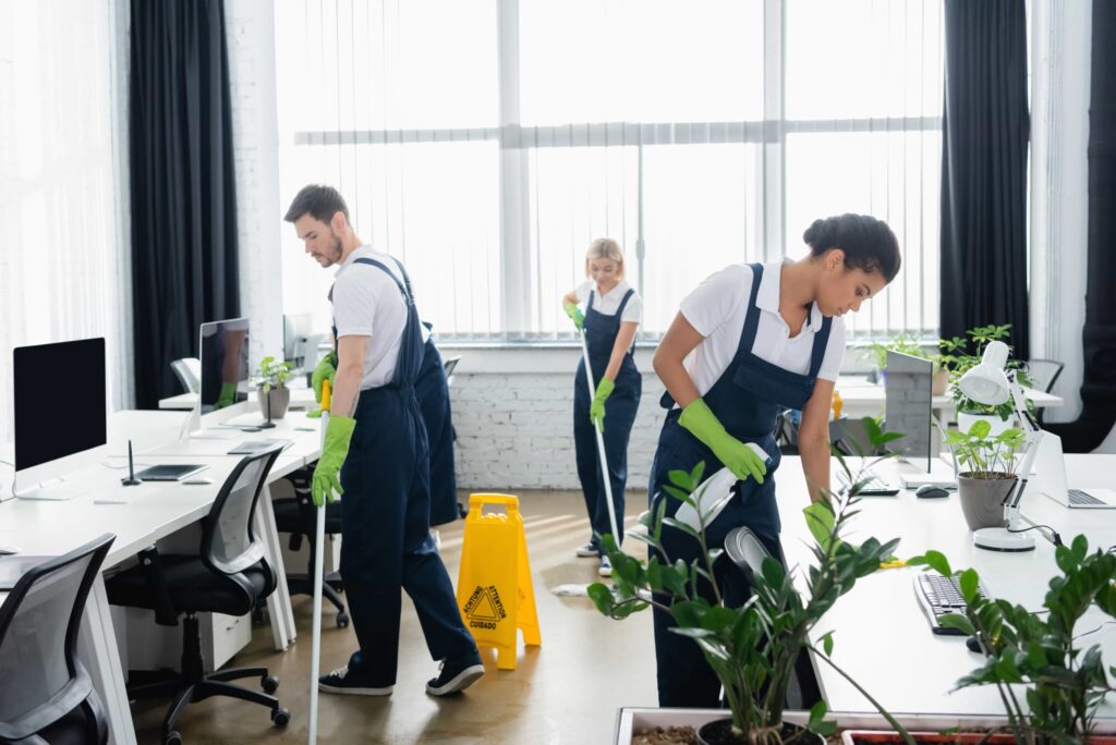 Team of cleaners mopping and wiping surfaces in an office.