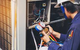 An HVAC technician checks gauges while servicing an outdoor unit.