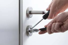 Hands repairing a door lock with tools.