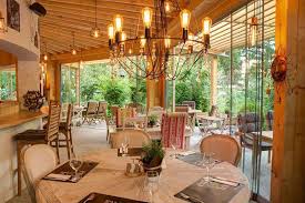 Outdoor restaurant seating under a canopy with plants.